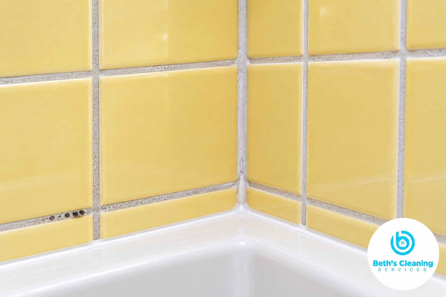 Dark spots along gray grout in a pale yellow tiled shower corner